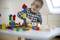A child plays intently with colourful building blocks on a table in a bright room.