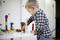 A child is playing with colourful building blocks on a table. The boy is wearing a checked shirt and is concentrating on constructing a structure.