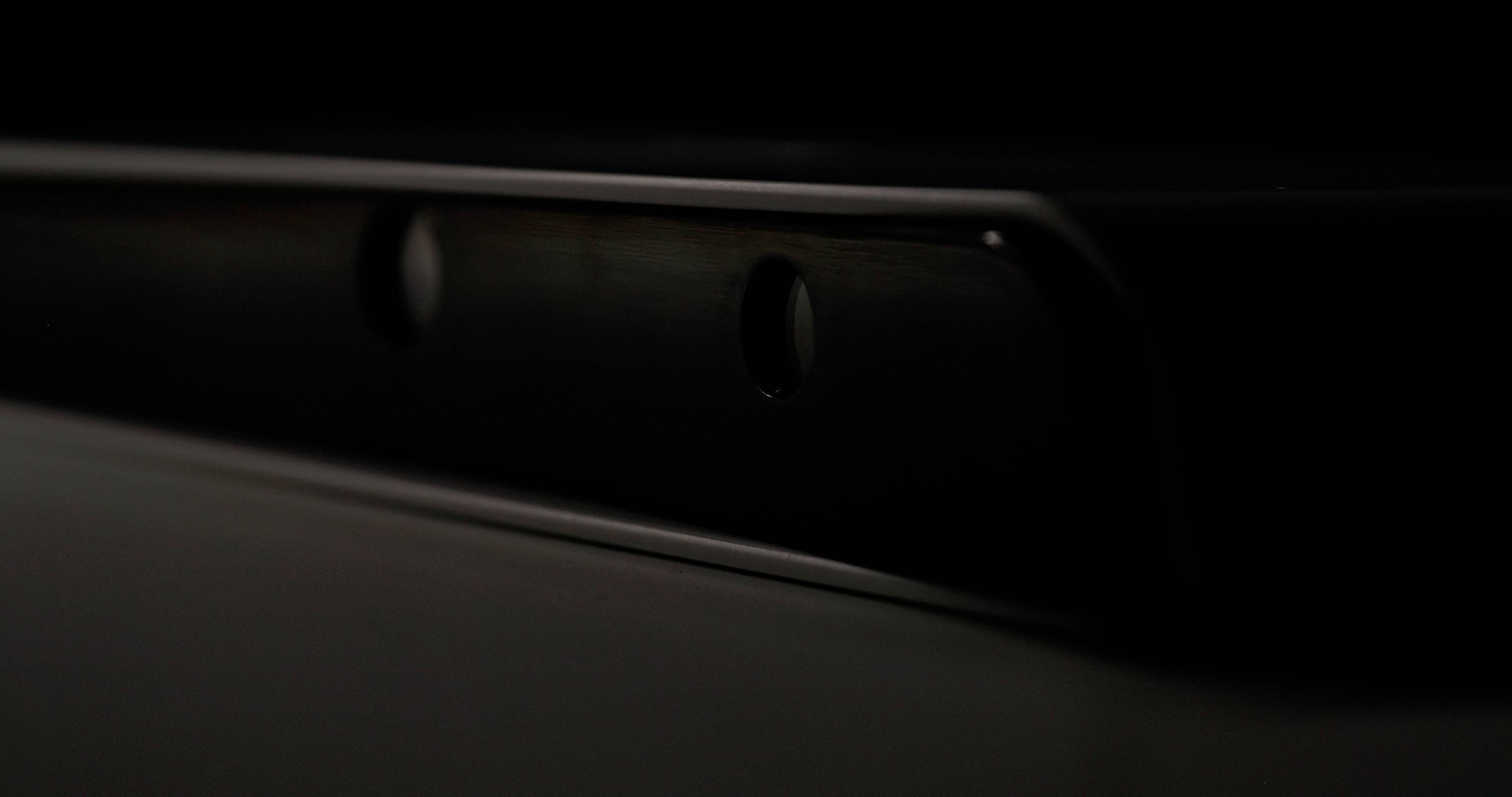 Dark, blurry image with two round openings on a metallic or technical device. Details barely discernible.