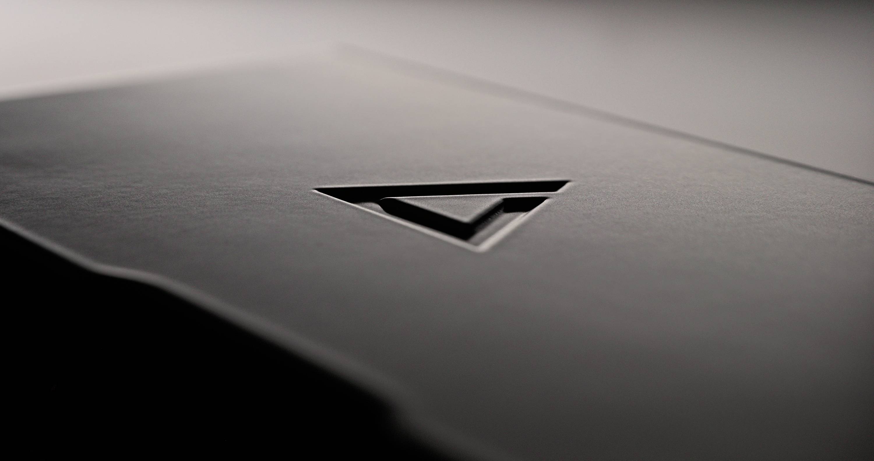 A black, rectangular object with an engraved arrow pointing downwards in the centre.