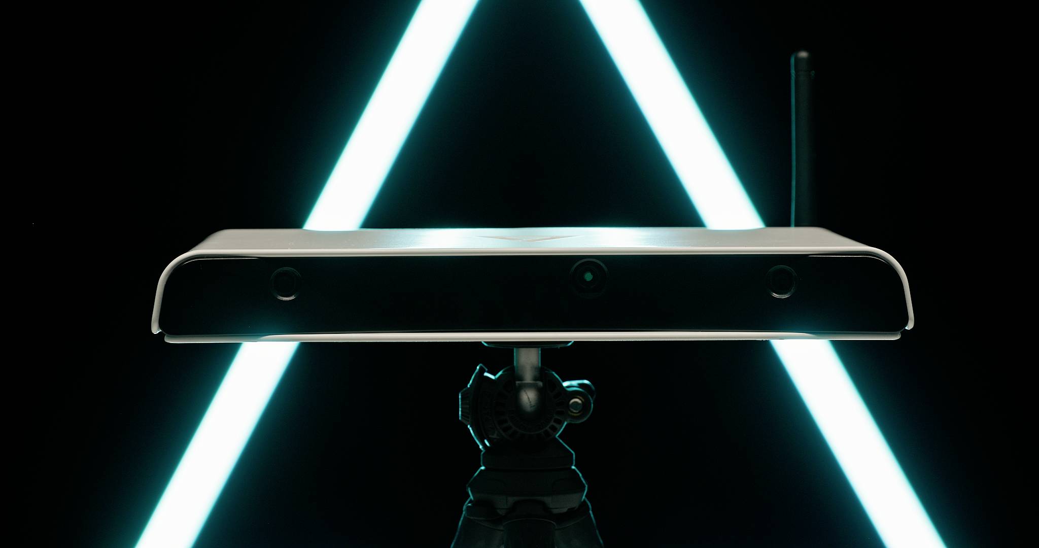 A rectangular device on a stand in front of a bright blue, triangular background. It has black sensors on the front.