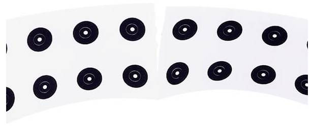 A curved arc of white paper with several black circles positioned at regular intervals upon it.