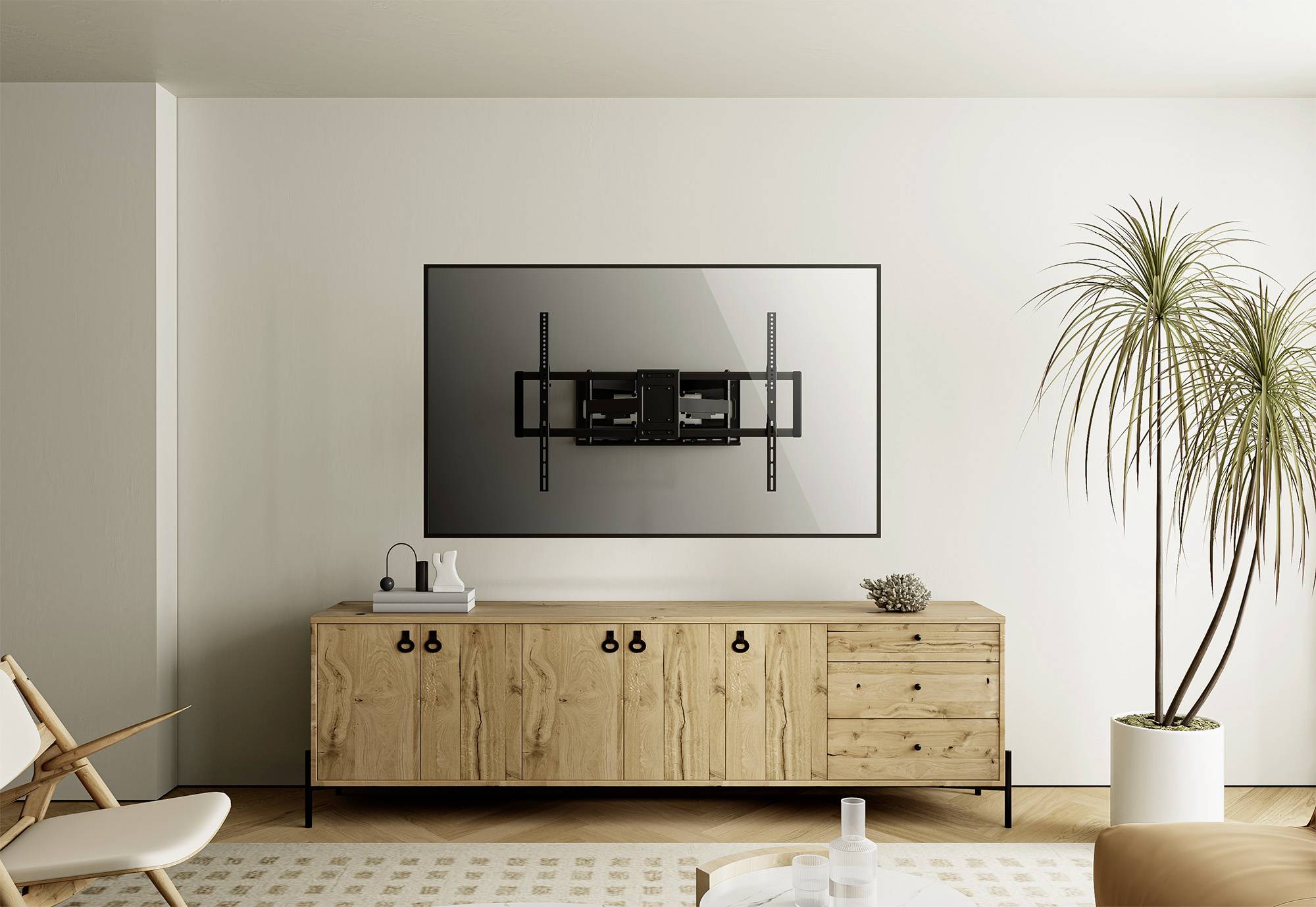 A modern living room with a wooden sideboard and a wall-mounted TV bracket on the wall. A plant stands beside the sideboard.