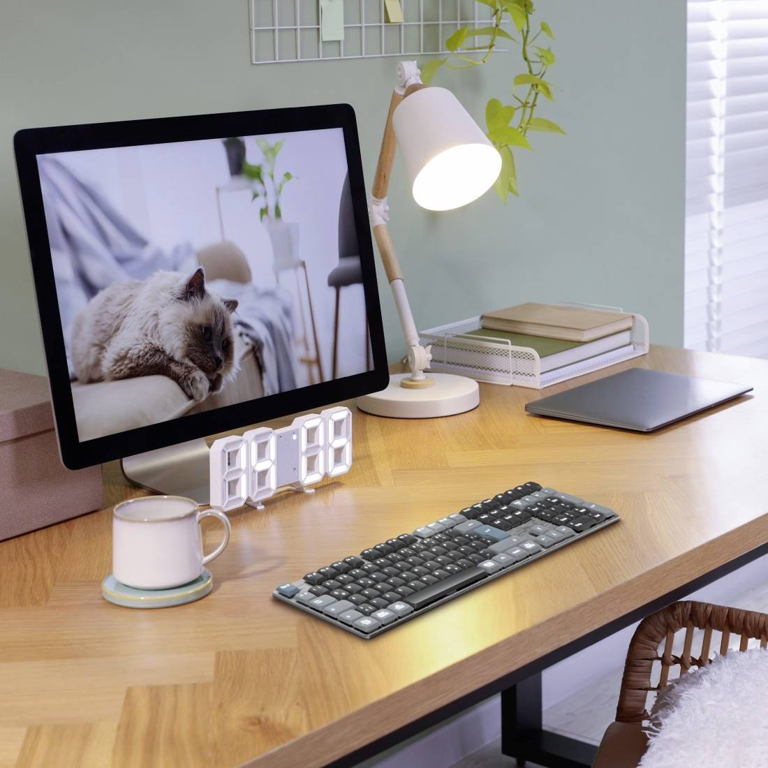 A modern wooden desk with a computer screen depicting a sleeping animal, a lamp, keyboard, and mug resting on its surface.