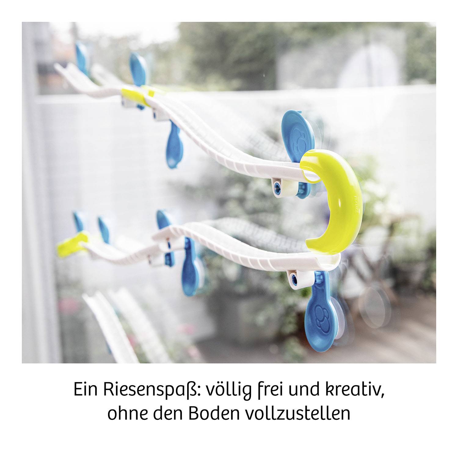 A toy with yellow and blue clips on a curved track, attached to a smooth surface, promises creativity.