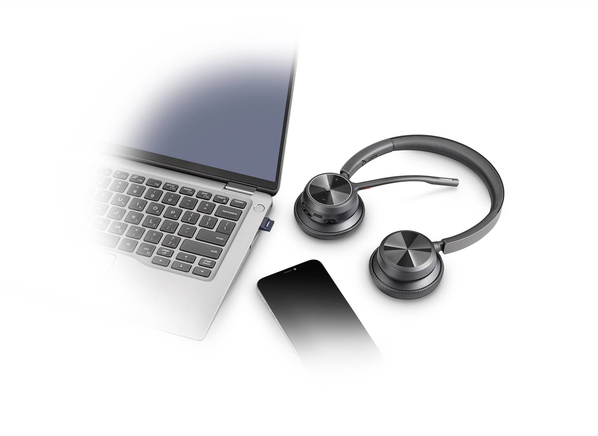 A laptop, a smartphone and wireless headphones are lying on a white surface. Focus on modern, interconnected technology.