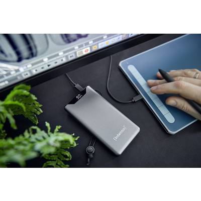 A portable external SSD storage device is being connected near a graphics tablet while graphic software runs on a screen.