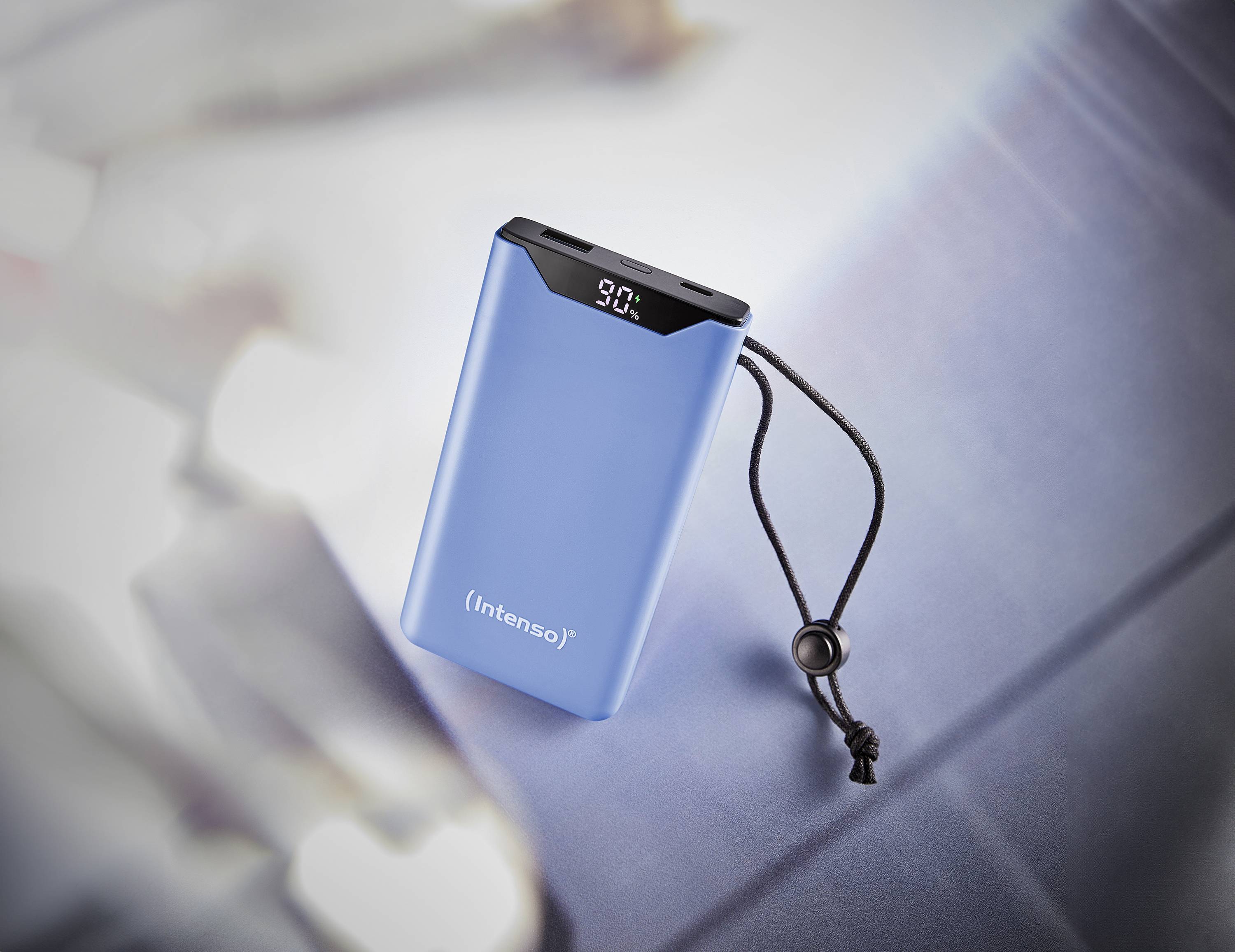 A blue portable power bank with a display showing 90% charge. It has a black elastic band on the side.