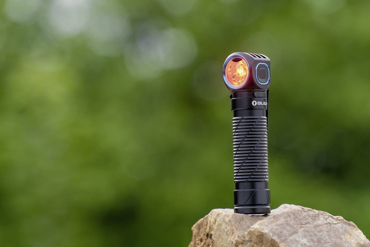 Torch with red light stands on a rock in front of a blurred green background.