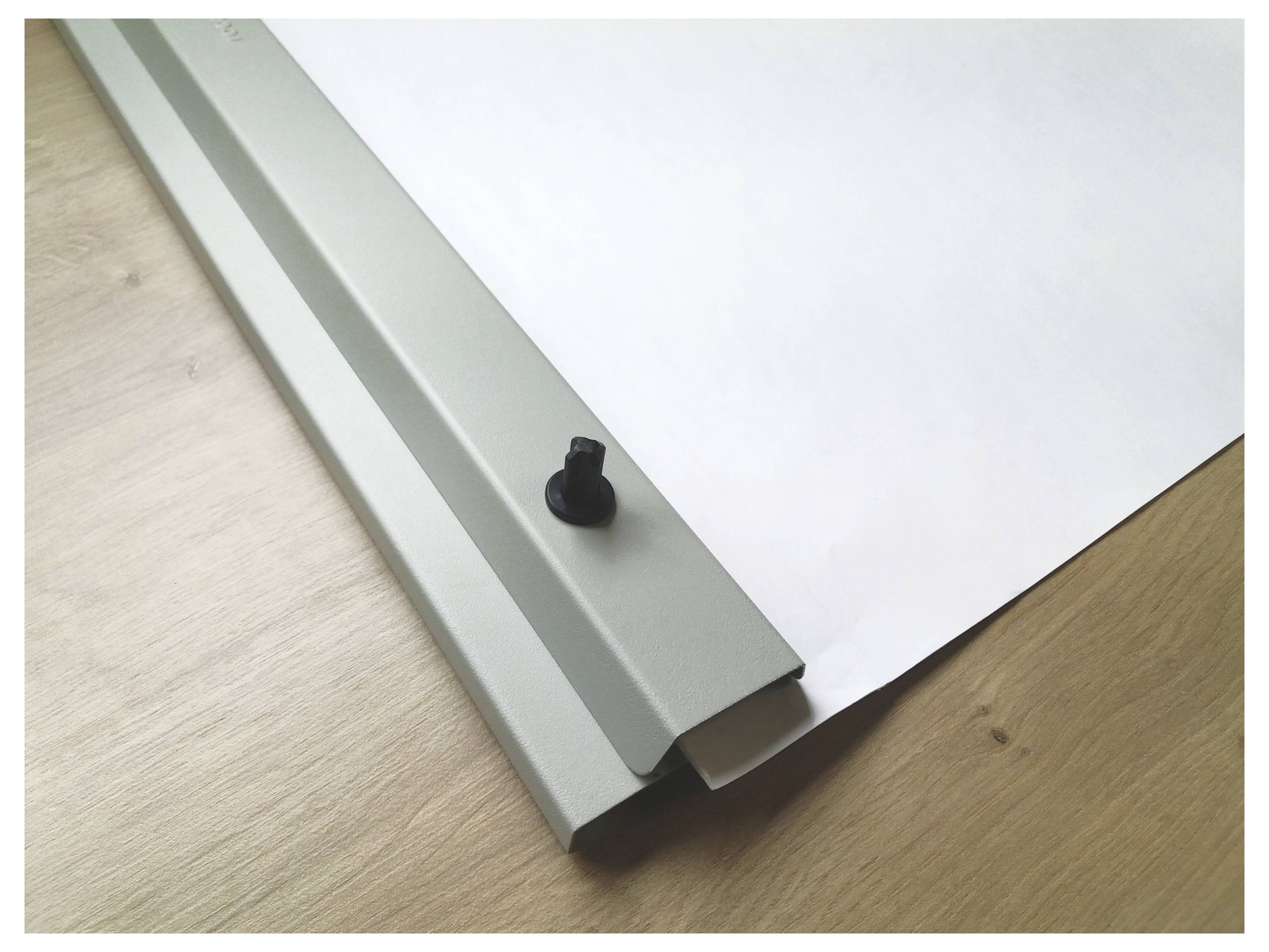 A white sheet of paper partially rolled into a silver metal strip on a wooden table.