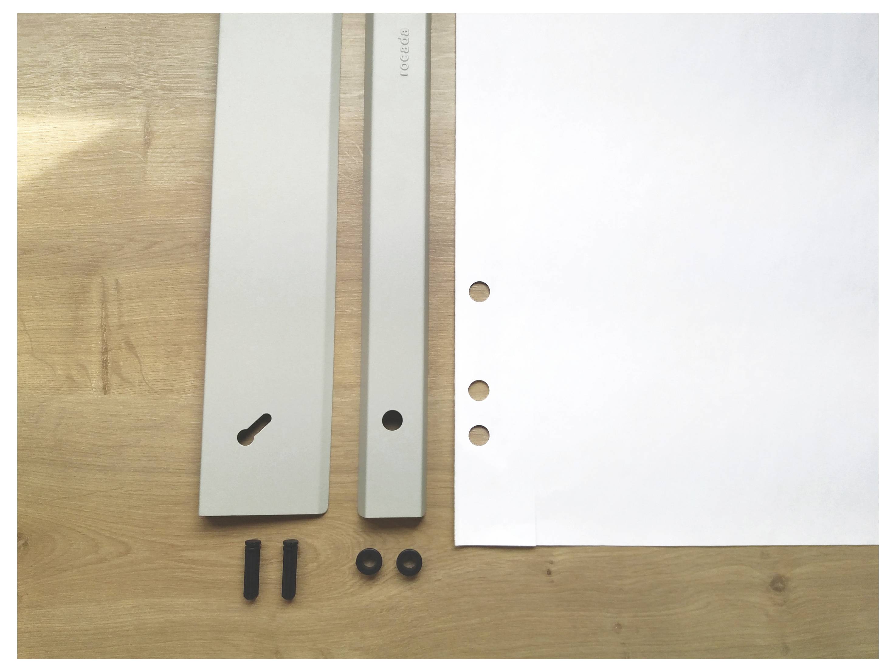 Two white metal beams and paper with holes on a wooden surface, with small black parts nearby. Preparation for a construction project.