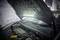 A car is parked with its bonnet open in a garage workshop. A diagnostic device is lying next to the engine to support maintenance work.
