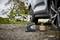 A car tyre is being inflated with a portable compressor, with a bicycle in the background on a country lane.