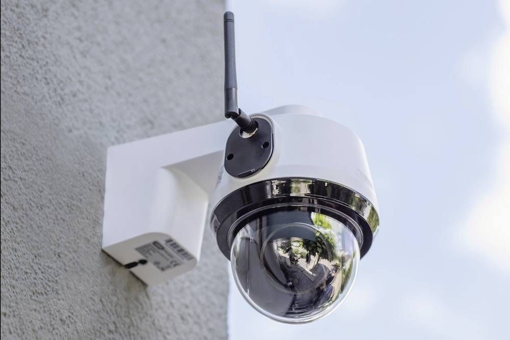 Security camera mounted on a building wall, monitoring the exterior area.