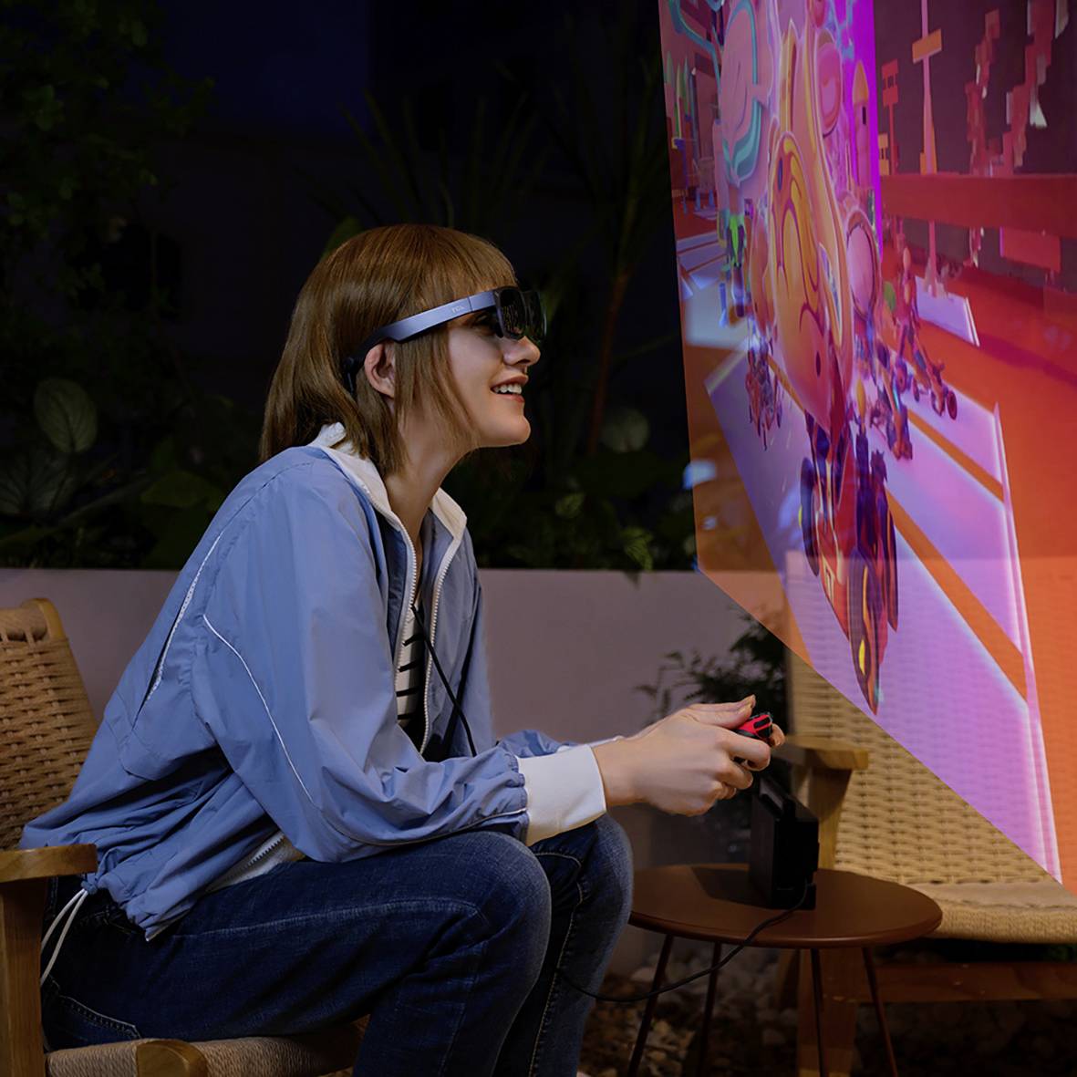 A person wearing a VR headset sits and looks enthusiastically at a virtual projection with colourful graphics.