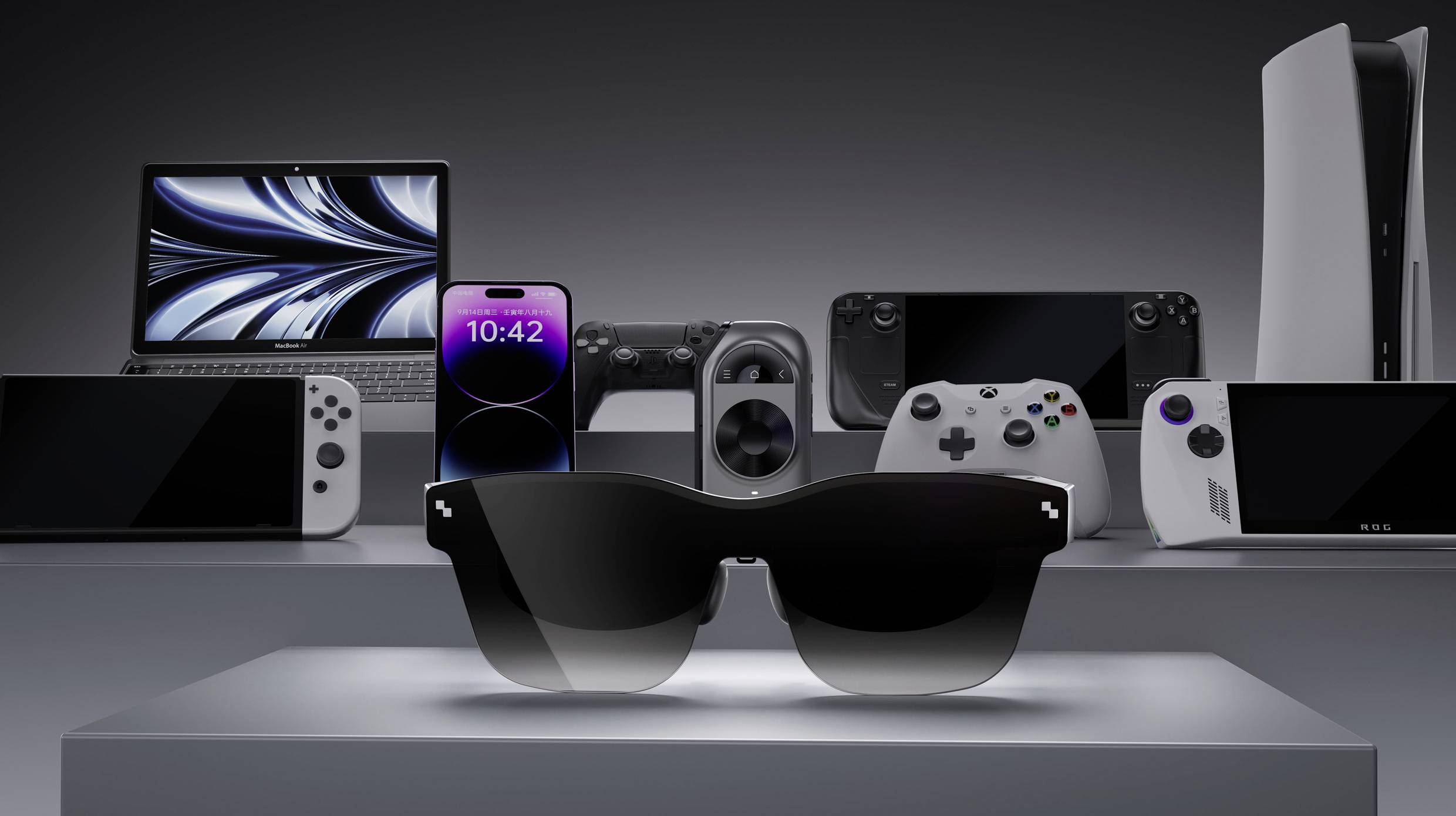 Sunglasses in the centre, surrounded by technological devices such as a laptop, smartphone and games console on a plinth.