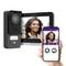 A woman smiles at the camera of a door entry system. A smartphone displays the woman's image.