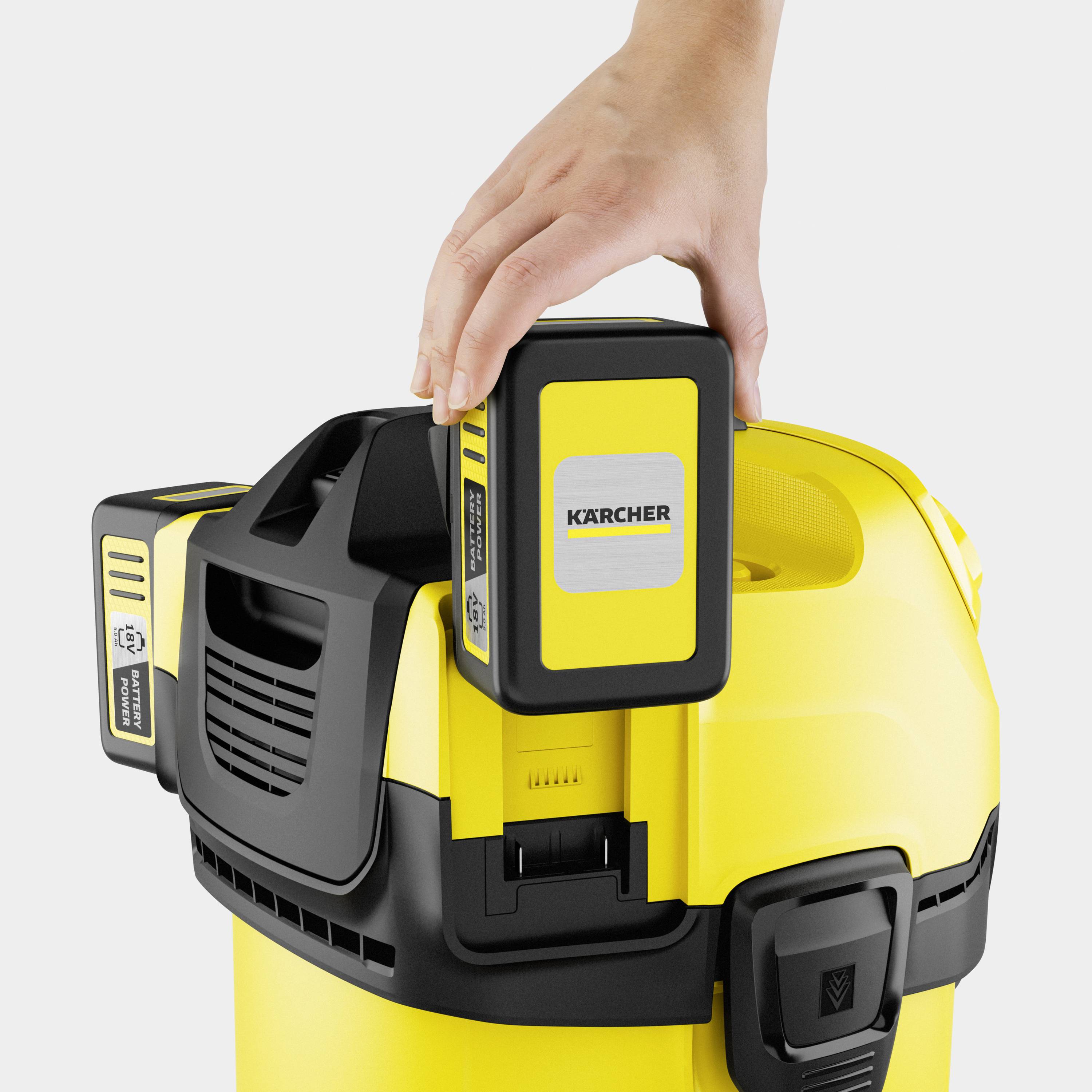 A hand is operating a yellow cleaning device from a well-known brand. The device has a function button and ventilation slots.