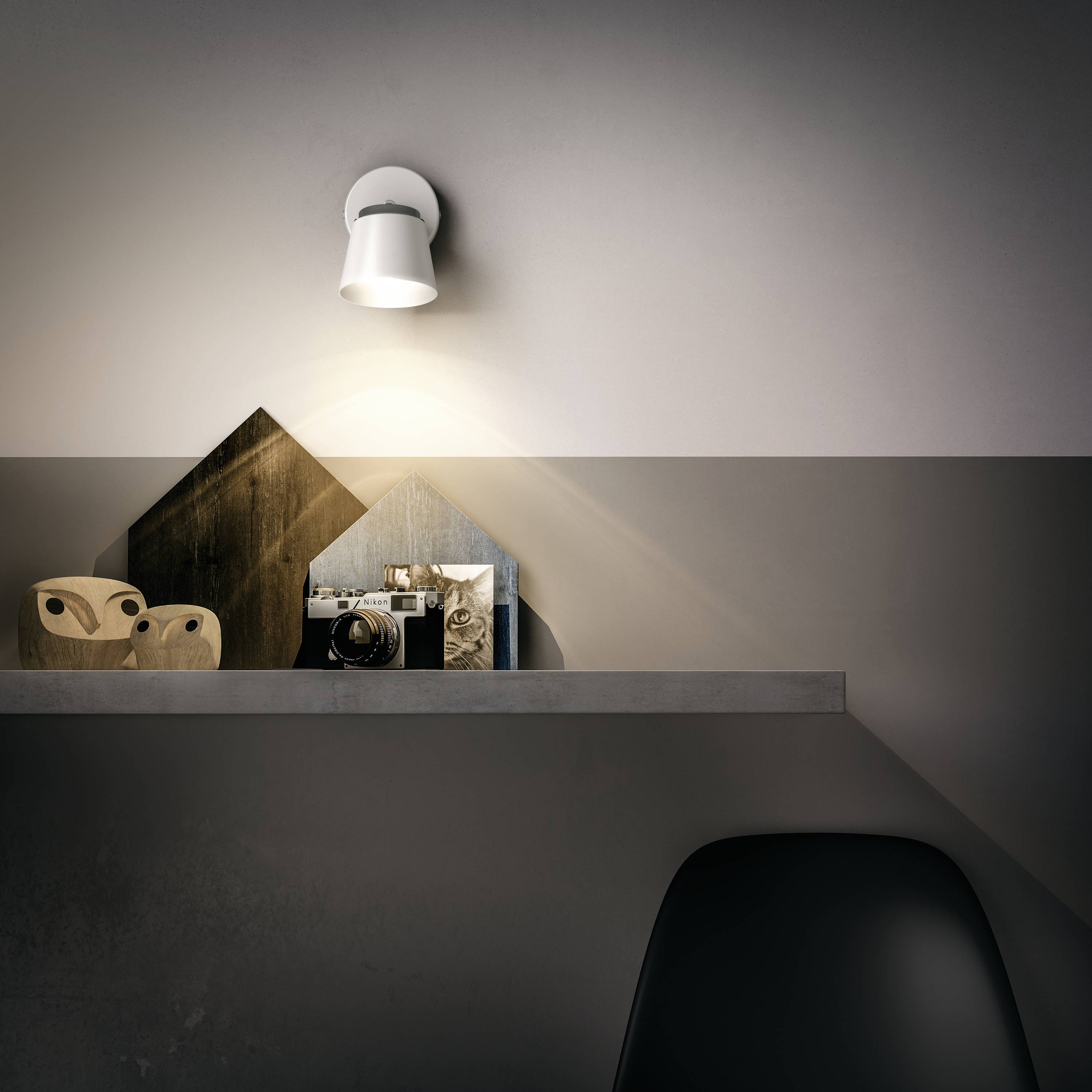 A modern wall shelf with decorative wooden objects, a framed picture and a camera. A wall light illuminates the display above.
