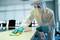 A person in protective clothing is disinfecting a table in an office.