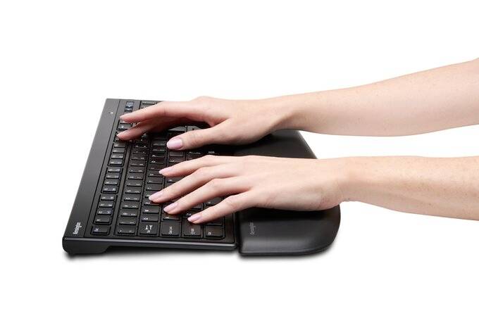 A person is typing on an ergonomic keyboard with a wrist rest.
