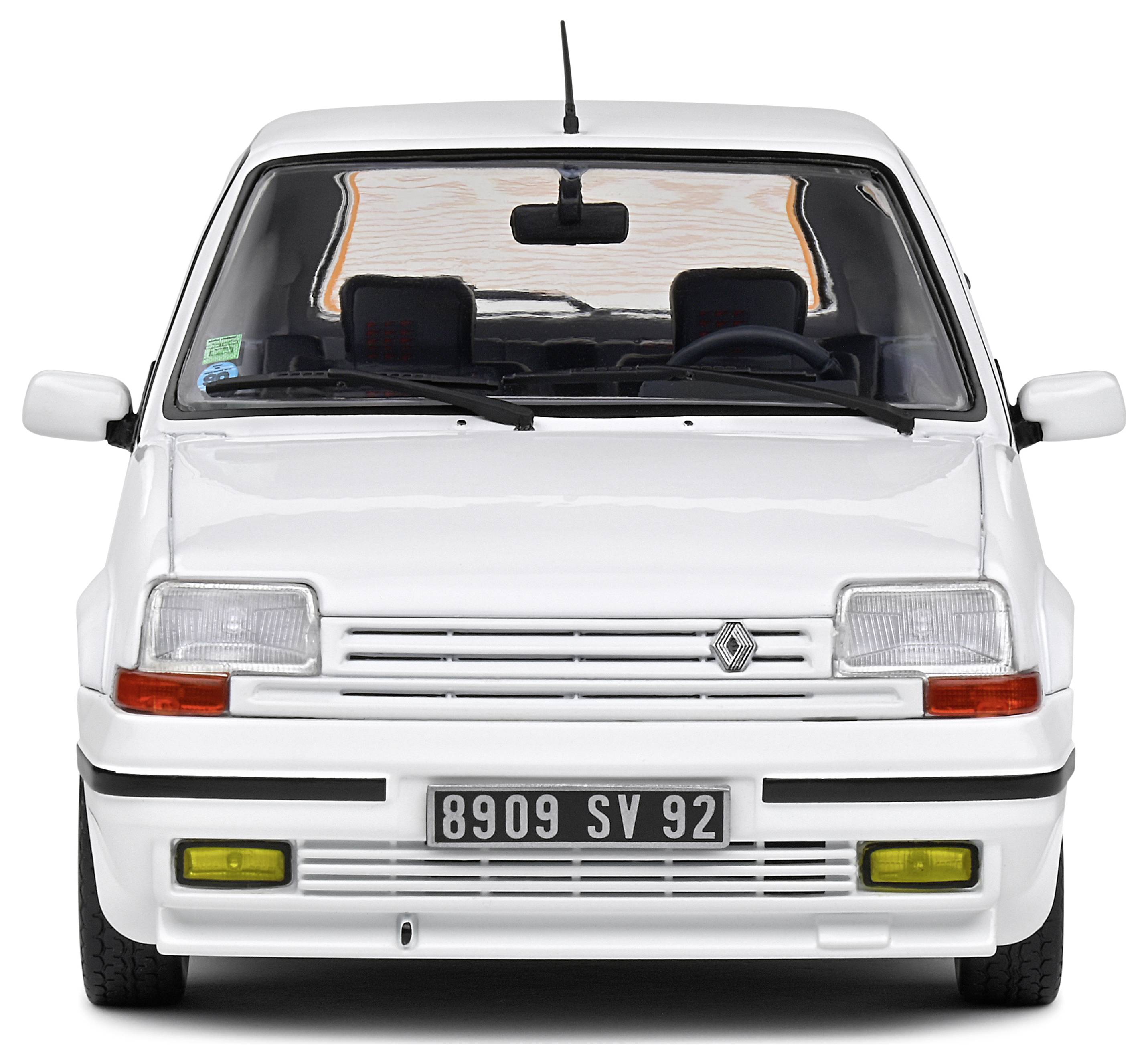 A white car photographed from the front, with a yellow fog light and a number plate underneath.