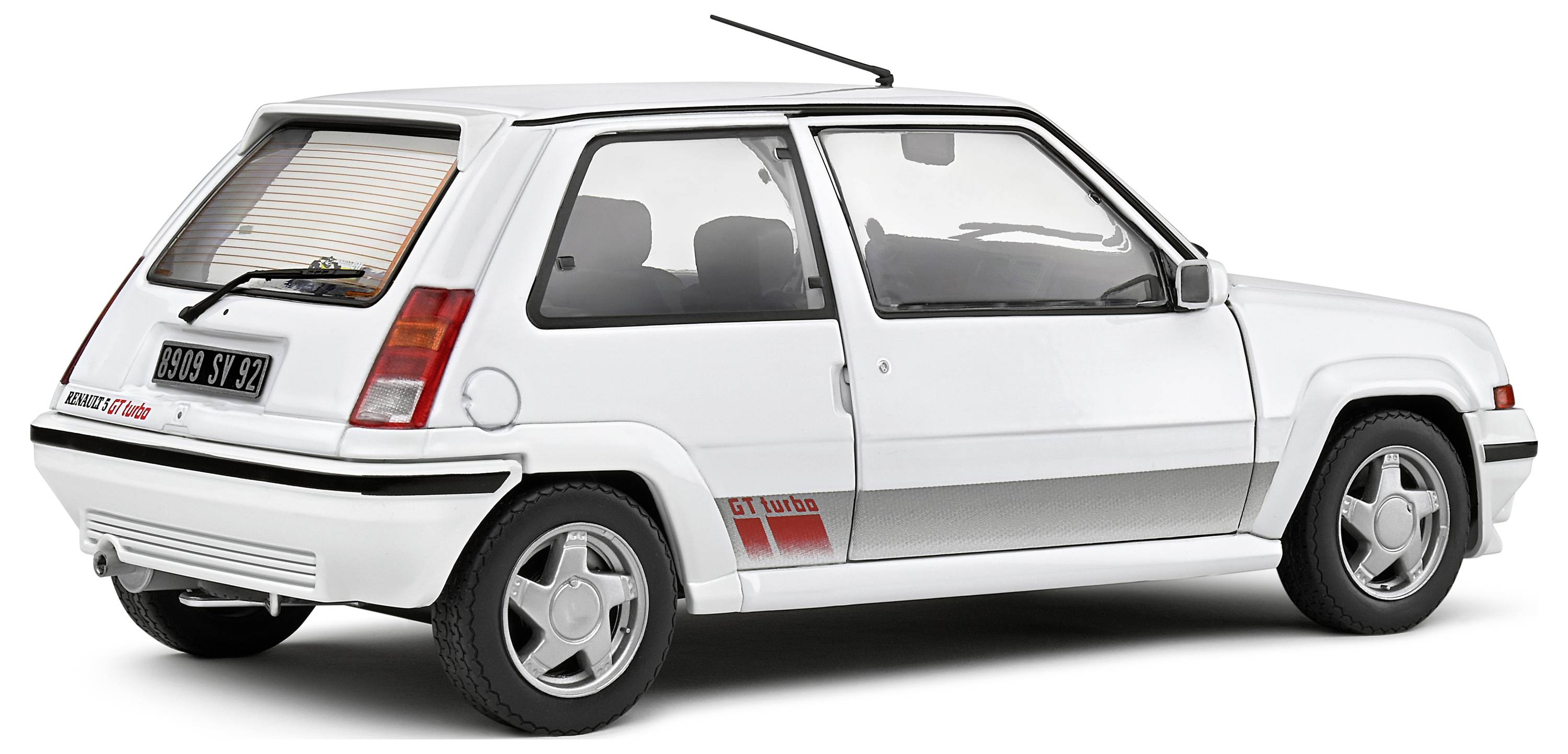 A white compact car with 'G7 turbo' written on its side, parked in a bright setting. The rear view reveals details such as tail lights and wheel trims.