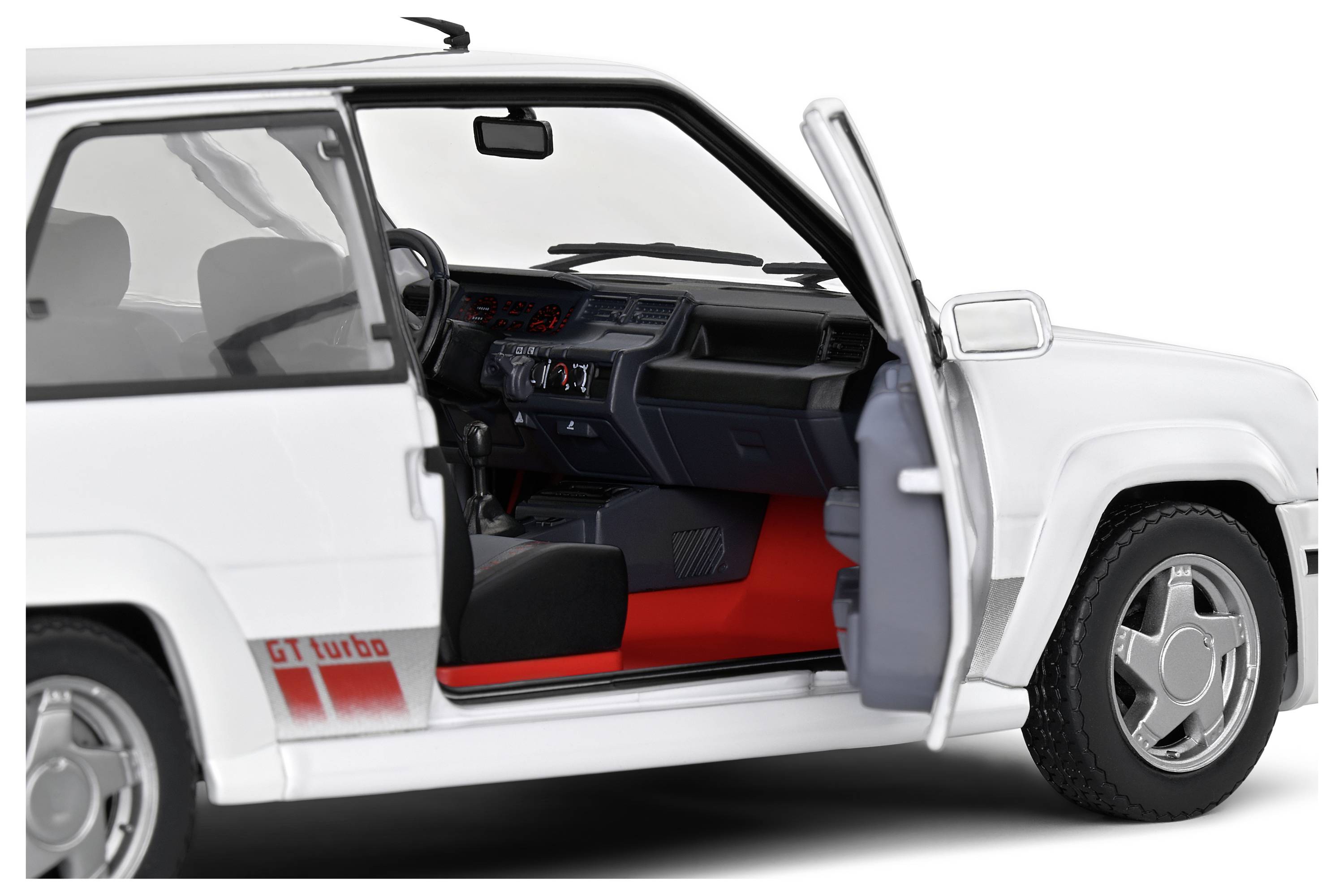 A white car with an open driver's door reveals its red interior and dashboard with various controls.