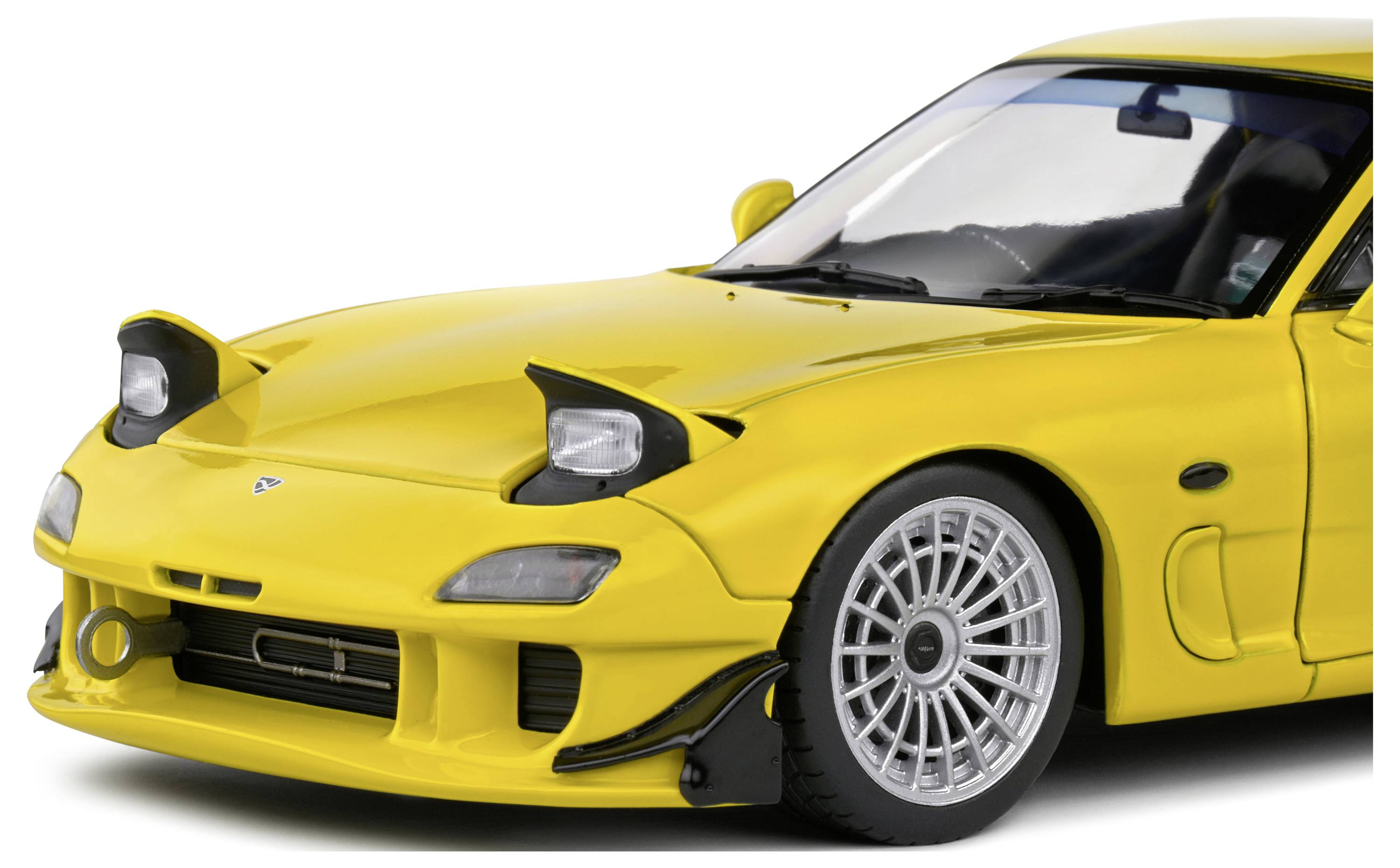 Yellow sports car with distinctive, raised headlamps and eye-catching alloy wheels, viewed from the front.