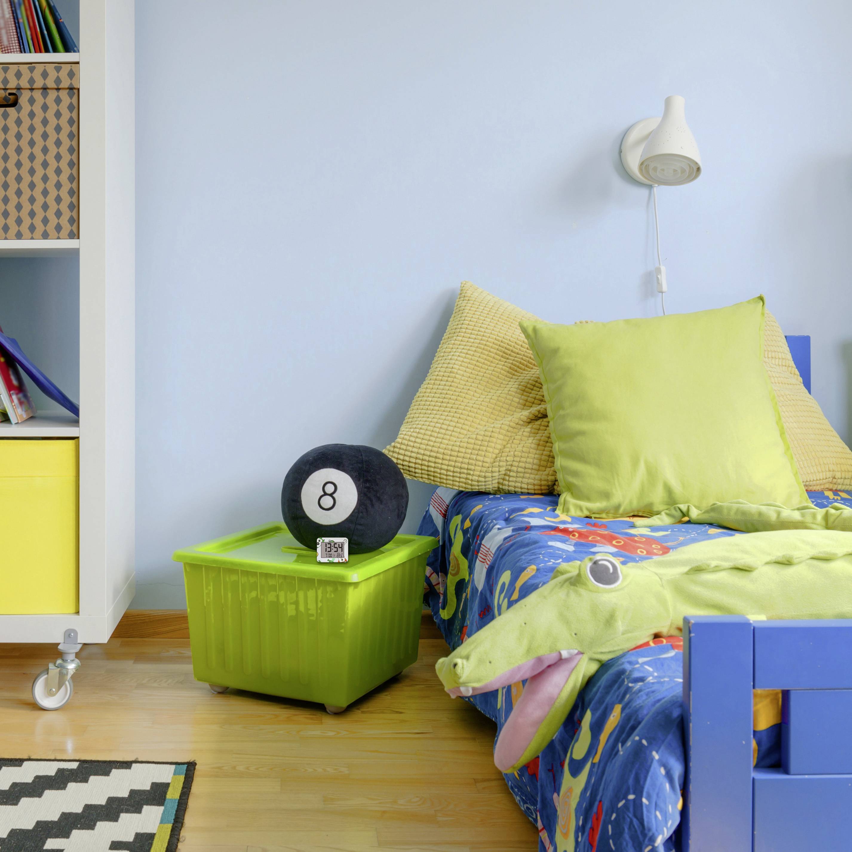 A colourful children's bedroom with a bed, cushions in green and yellow, and a toy box with the number 8 in a green crate.