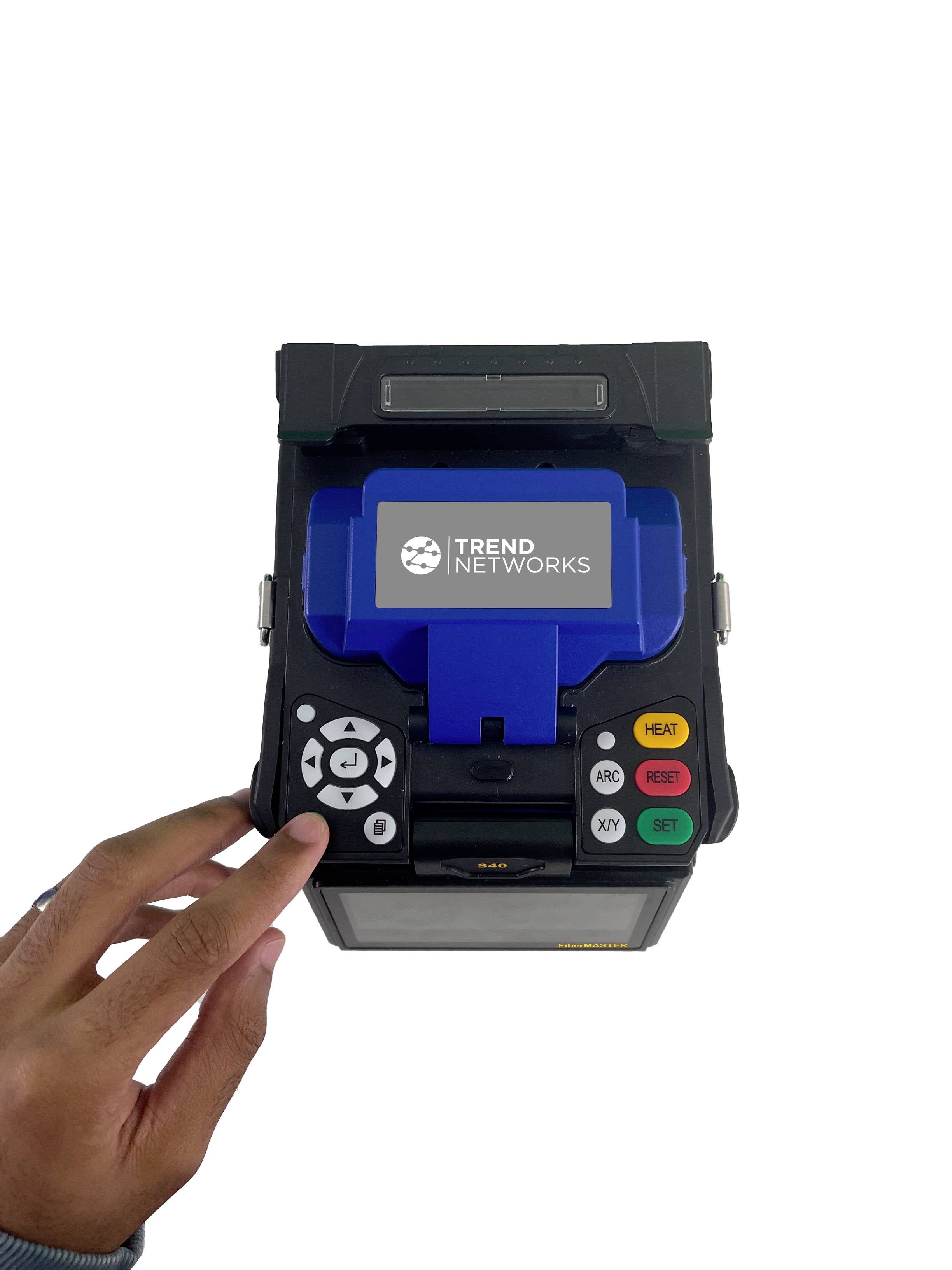 A device with a screen displaying 'Trend Networks'. A hand is operating the buttons.
