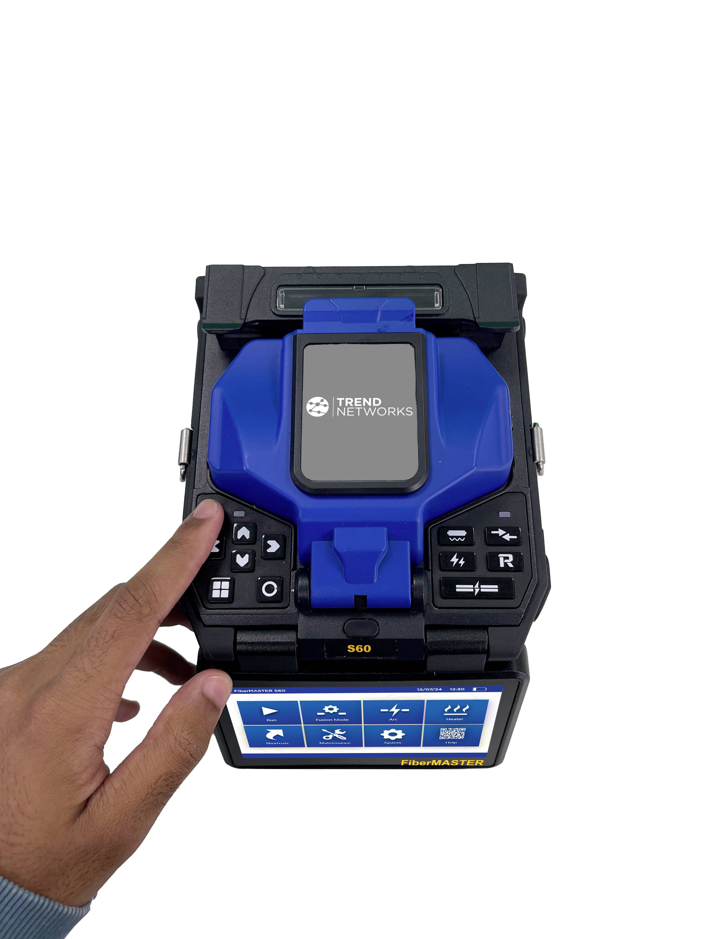 A hand is operating a device with a display and multiple buttons. It is a technical device for network measurement.