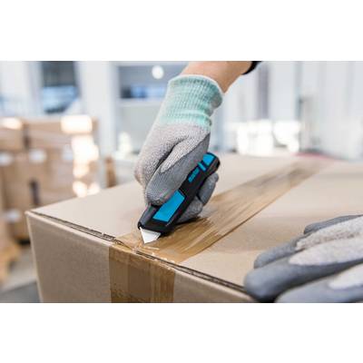 A person wearing gloves is cutting adhesive tape with a craft knife on a cardboard box in a warehouse.