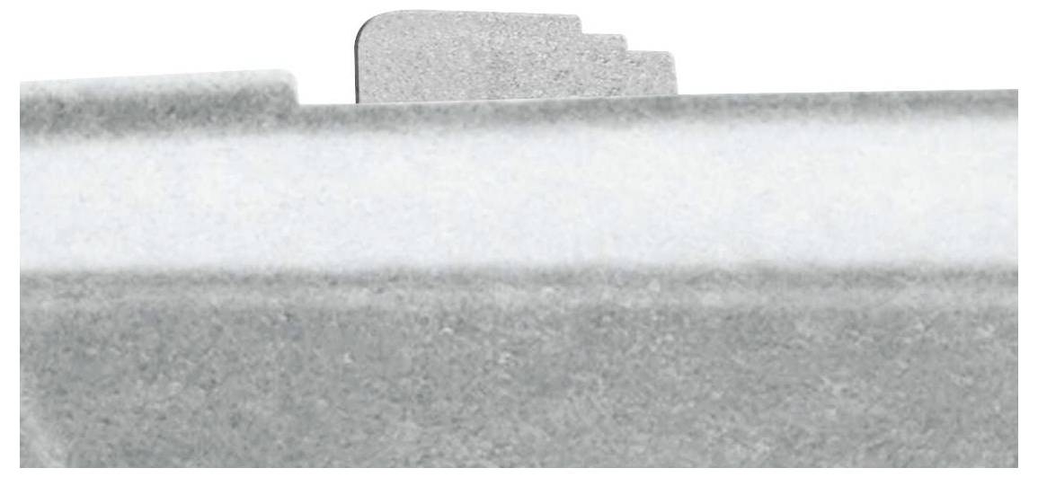 A grey structured object with a stepped edge protrudes from a smooth surface.