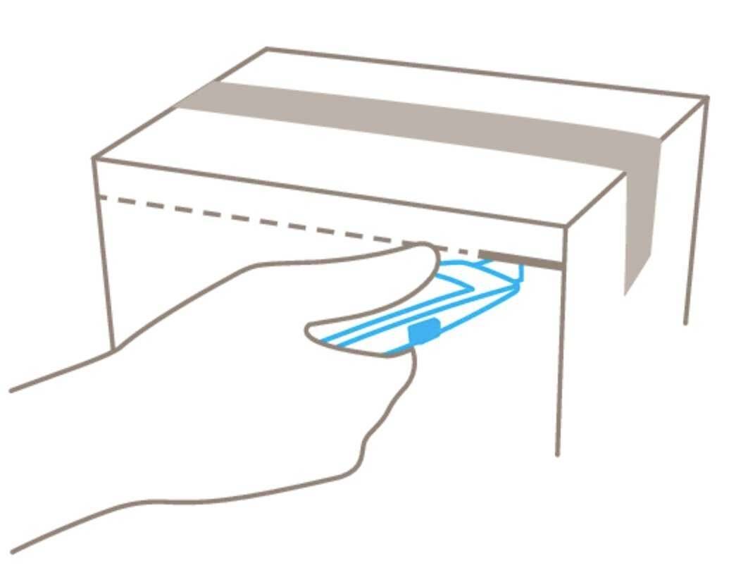 A hand slides a cardboard sleeve under the flap of a box to secure the packaging.