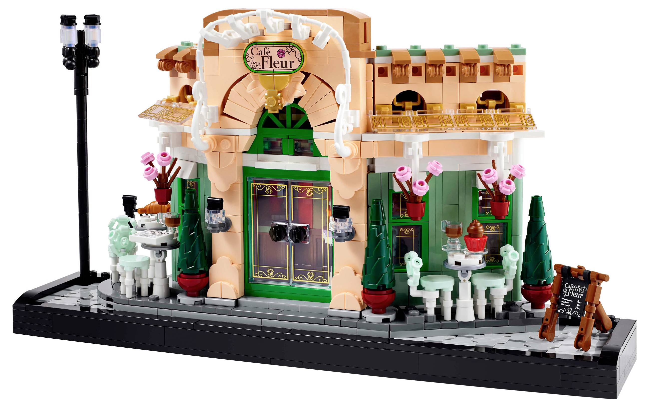 A stylish café building made of LEGO bricks with colourful façade details, tables and chairs. A small chalkboard is positioned in the foreground.