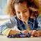 A child plays happily with a small model car that is sitting on a table. The car is intricately designed and colourful.