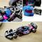 A model car in black with pink and blue accents, surrounded by a helmet and a controller.