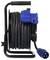 Pictured is a black cable reel with a blue plug and socket. It is completely wound up on a black metal frame.