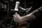 'Close-up of a mechanic working on a gearbox with a hammer. The room is lit in a workshop-like manner.'