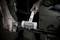 A person is using a white SUPERCRAFT hammer to secure an automotive part on a metal rod in a workshop.