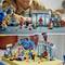 A child is playing with building blocks and superhero figures at a table. The figures are colourful and set against an urban backdrop.