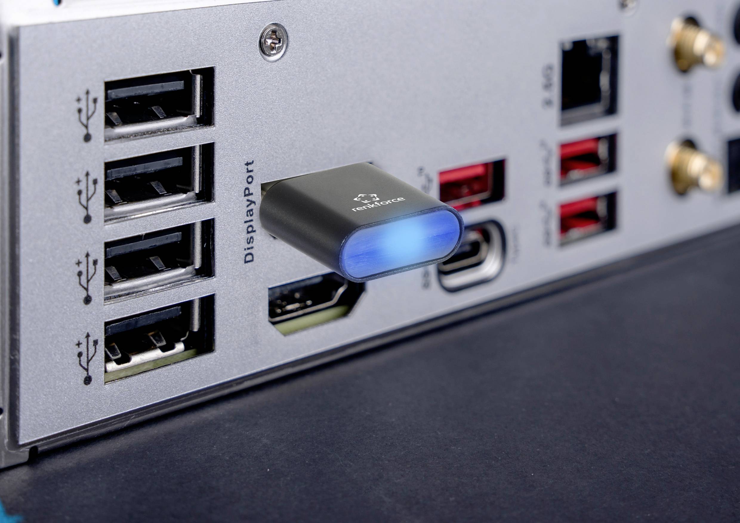 'Back of a computer with various ports and a USB stick plugged in with a blue illuminated LED indicator.'