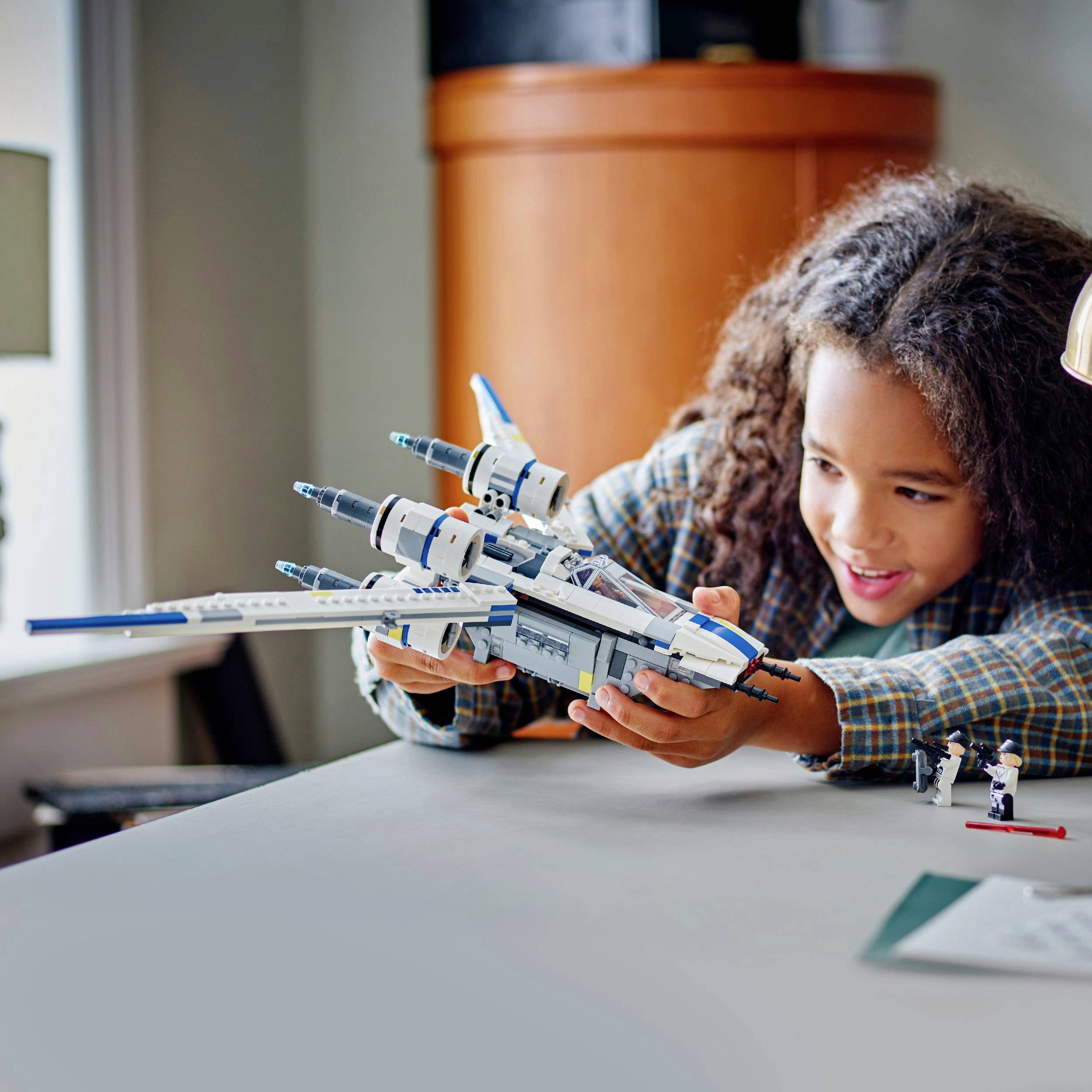 A child is playfully enjoying a model spacecraft on a table, inspired by science fiction.