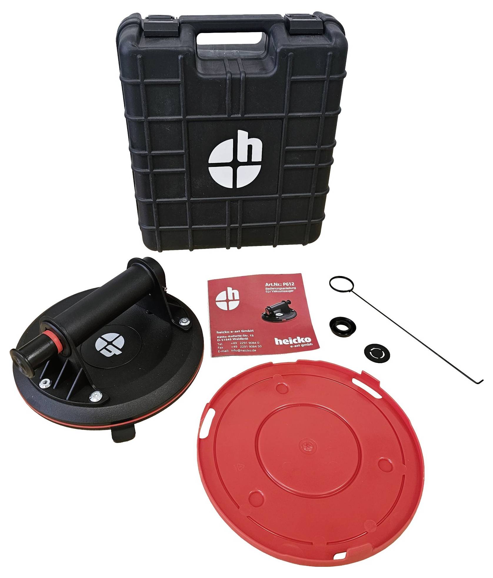 A black vacuum lifter with a red protective cover, spare parts, and operating instructions, placed in front of a black case.