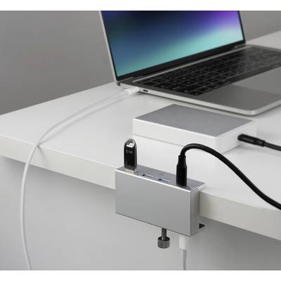 A laptop with an open screen sits on a table. A USB hub is connected, and a USB stick and cable are plugged in.