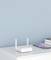 A white Wi-Fi router with two aerials sits on a white table next to a mobile phone and books in front of a blue wall.