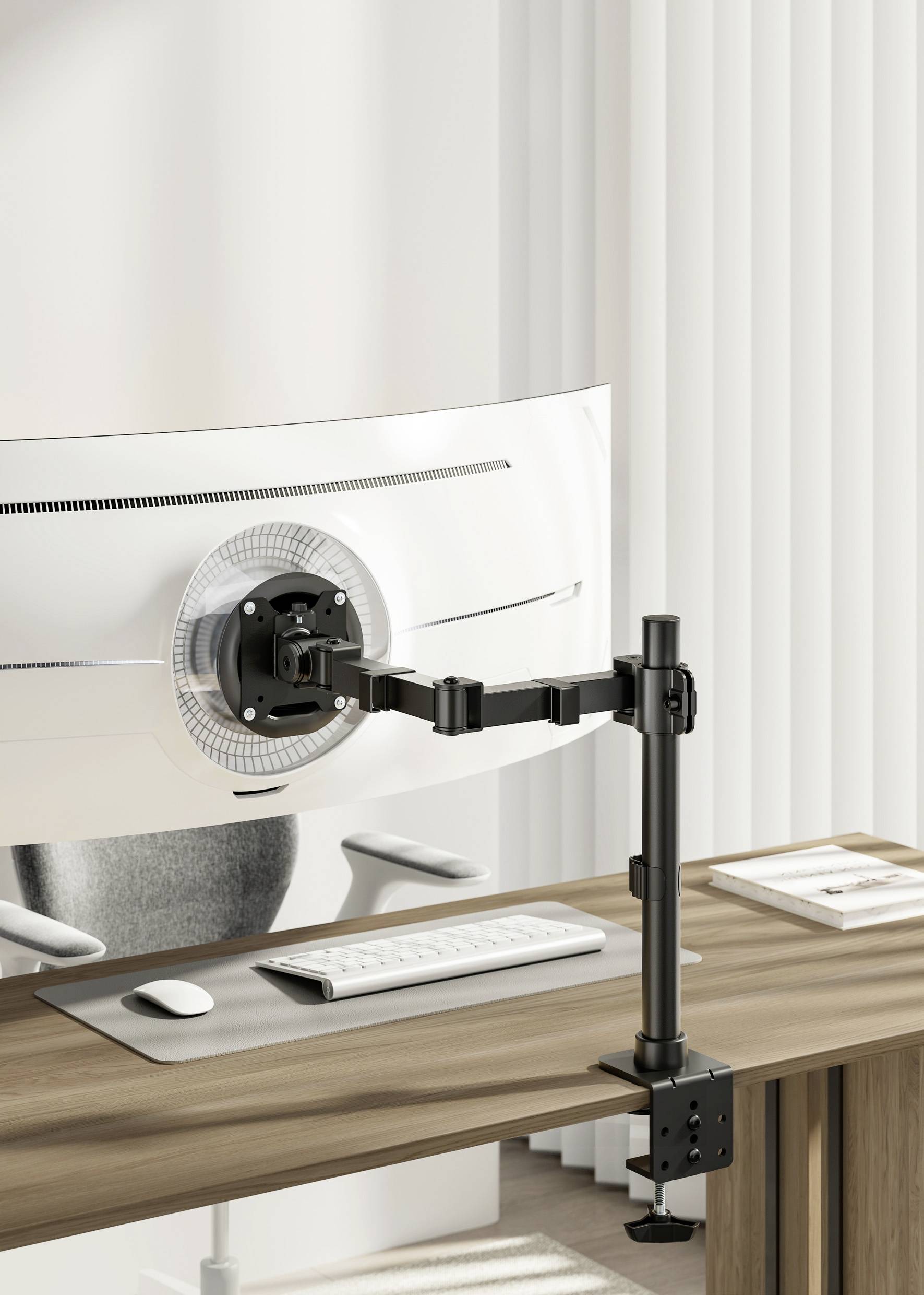 Monitor mount attached to a desk, holding a curved screen. Keyboard and mouse positioned underneath on a wooden table.