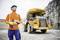 A construction worker in orange protective clothing stands in front of a large yellow dump truck in a quarry.