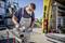 A worker is cutting metal grating with a saw next to a van. He is wearing safety protection such as a mask, gloves and safety glasses.